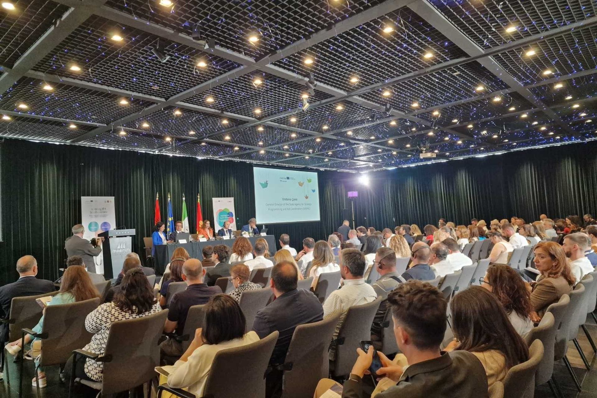 Na zvaničnoj ceremoniji održanoj 18. juna 2025. u Tirani, Ministarstvo socijalnog staranja, brige o porodici i demografije predstavljeno je kao vodeći i punopravan partner u okviru dva značajna projekta Interreg IPA programa Južni Jadran 2021–2027, čime potvrđuje svoju ulogu u jačanju regionalne saradnje i promociji evropskih vrijednosti.

Na događaju posvećenom promociji prekogranične saradnje zemalja regiona Južnog Jadrana, Ministarstvo socijalnog staranja, brige o porodici i demografije preuzelo je vodeću ulogu u realizaciji projekta Religious R.O.A.D., koji ima za cilj očuvanje zajedničkog kulturnog nasljeđa i promociju međureligijskog dijaloga. Projekat takođe podstiče interkulturno razumijevanje i doprinosi jačanju društvene kohezije.
Pored toga, Ministarstvo učestvuje i kao punopravan partner u projektu GOAL HEALTH, usmjerenom na unapređenje integrisanih zdravstvenih i socijalnih usluga, posebno za osjetljive društvene grupe. Kroz razmjenu dobrih praksi s institucijama iz drugih zemalja, projekat ima za cilj razvoj inovativnih rješenja za inkluzivniju i otporniju zajednicu.
Ceremoniju su otvorili Claudio Polignano, rukovodilac Upravljačkog tijela Interreg IPA programa za Južni Jadran, i Gilles Kittel iz Generalnog direktorata za regionalnu i urbanu politiku Evropske komisije. U svojim obraćanjima istakli su važnost ovakvih projekata za jačanje povezanosti i otpornosti lokalnih zajednica u regionu.
Ministarstvo su na ceremoniji predstavljale Granica Simićević, načelnica Odjeljenja za programiranje i implementaciju EU fondova, i Jelena Banašević, službenica za programiranje. Nakon zvaničnih govora, organizovana je radionica za vodeće partnere na kojoj su predstavljene procedure i obaveze vezane za implementaciju projekata.
Ministarstvo je potvrdilo svoju posvećenost sprovođenju projekata koji promovišu evropske vrijednosti i doprinose razvoju socijalnih politika i očuvanju kulturnog identiteta regiona.